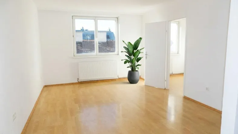 Helles, leeres Zimmer mit Parkettboden und großem Fenster, bereit zur individuellen Gestaltung.