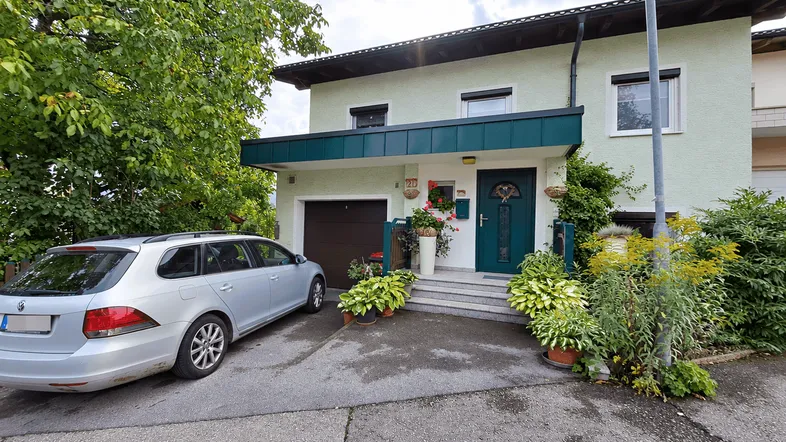 Vorderansicht des Hauses mit Garage, Vorgarten und gepflasterter Einfahrt.