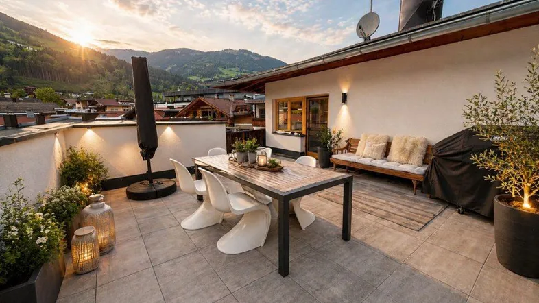 Geräumige Dachterrasse mit modernen Gartenmöbeln, Bergblick und Abendsonne.