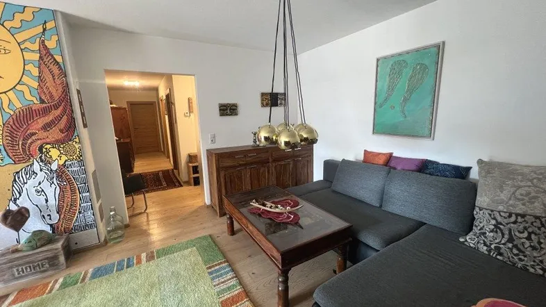 Gemütliches Wohnzimmer mit großem Sofa, Holzdielenboden und farbenfroher Dekoration.