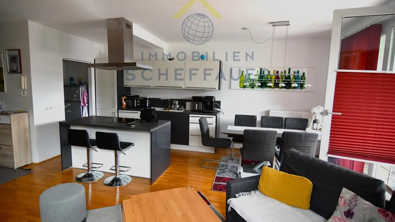 Heller offener Wohn- und Essbereich mit integrierter Küche, Holzboden und moderner Einrichtung.