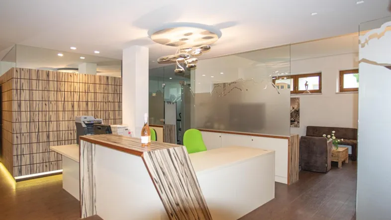 Moderner Empfangsbereich mit Holzakzenten, Glaswänden und stilvoller Deckenbeleuchtung.