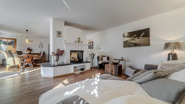 Heller offener Wohn- und Essbereich mit Kamin, Holzboden und gemütlichem Sofa.