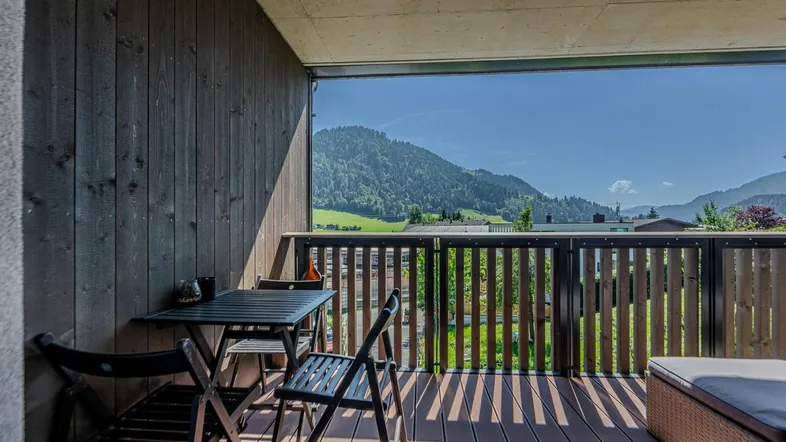 Geräumiger Balkon mit Holzboden, Sitzgelegenheiten und malerischem Bergblick.