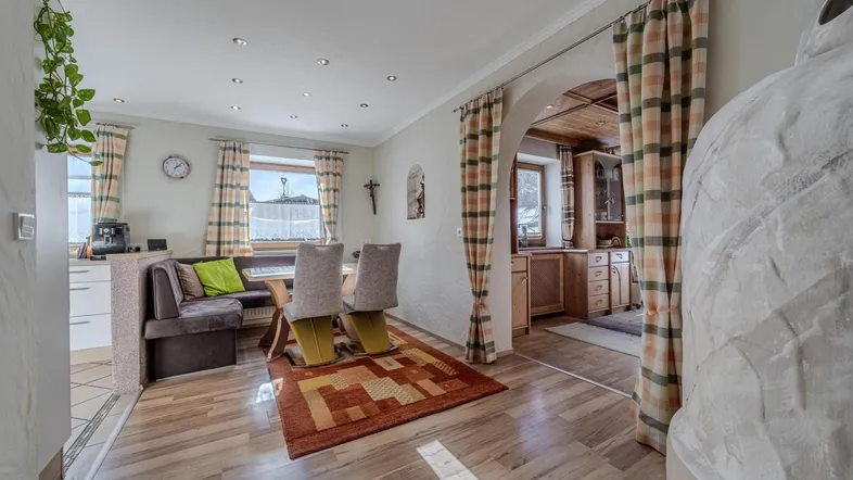 Helles Esszimmer mit Holzboden, gemütlicher Sitzecke und offenem Zugang zur Küche.