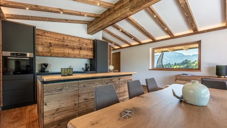 Moderne Küche mit Holzelementen, Essbereich und Bergblick durch das Fenster.