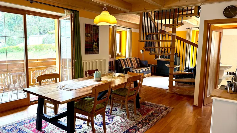 Geräumiger Wohn- und Essbereich mit Holzbalkendecke, Parkettboden und Zugang zum Balkon.