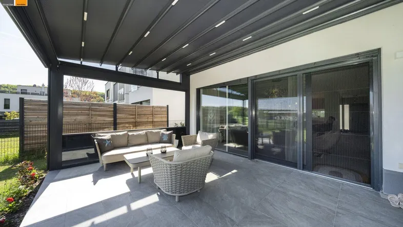Geräumige Terrasse mit bequemen Gartenmöbeln und ausfahrbarem Sonnenschutz, ideal zum Entspannen im Freien.
