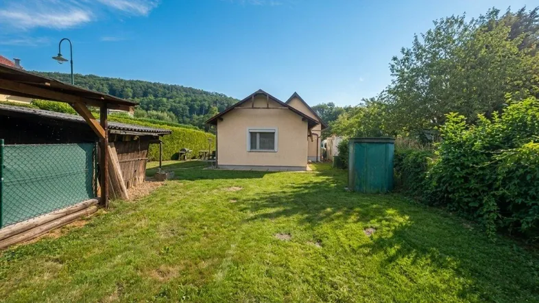 Großer Gartenbereich mit Rasenfläche, Nebengebäude und Blick auf die umliegende Landschaft.