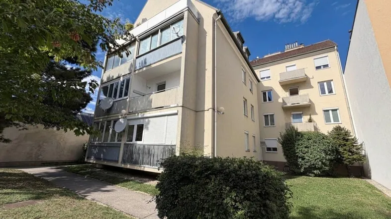 Außenansicht eines Mehrfamilienhauses mit Balkonen und gepflegten Grünflächen im Vordergrund.