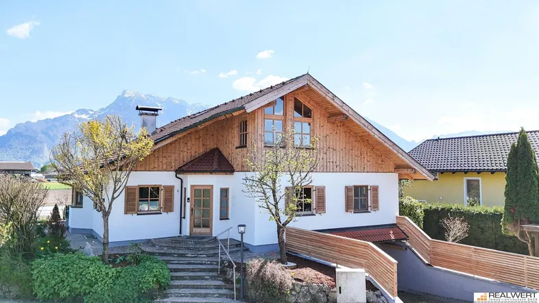 Traditionelles Haus mit Holzfassade und Satteldach vor beeindruckender Bergkulisse.
