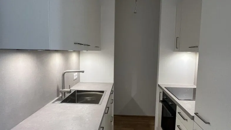 Moderne Einbauküche mit weißen Schränken, integrierter Spüle und Kochfeld, ideal für effizientes Kochen.