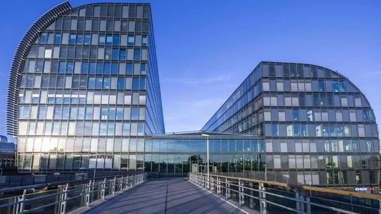 Moderne Bürogebäude mit Glasfassaden und einer verbindenden Brücke unter klarem Himmel.