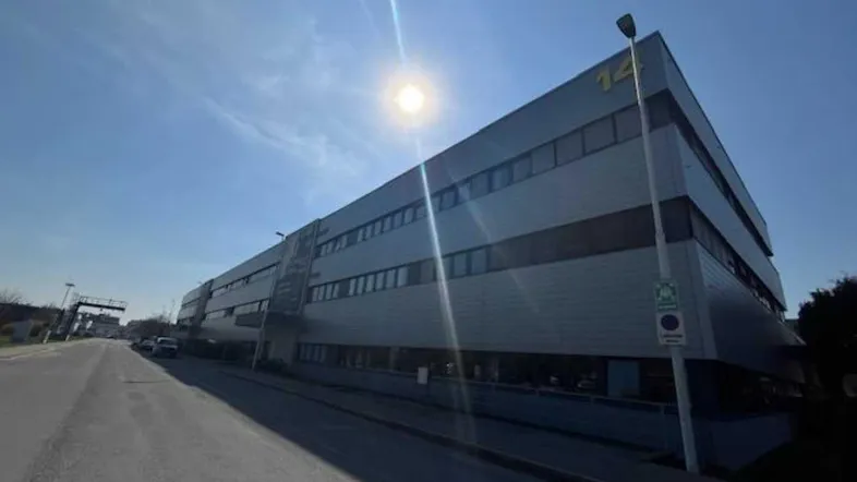 Modernes Bürogebäude mit vielen Fenstern und einer klaren Architektur unter strahlendem Sonnenschein.