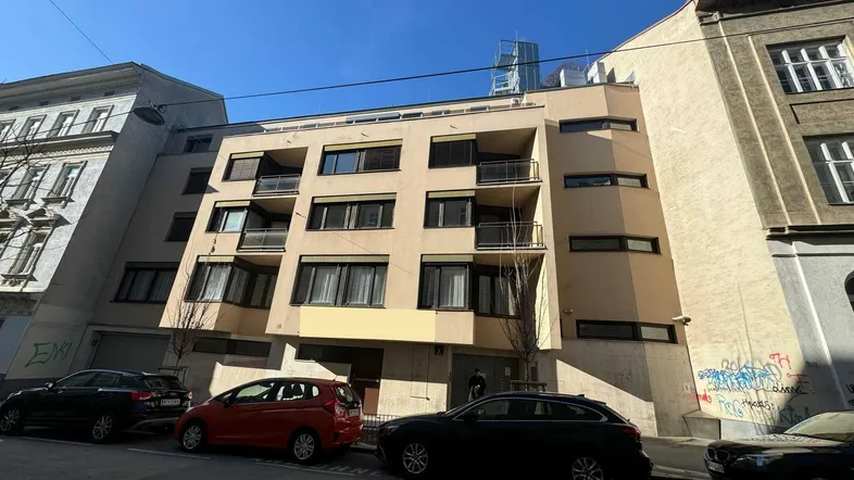 Fassade eines modernen Mehrfamilienhauses mit Balkonen und großen Fenstern an einer städtischen Straße.