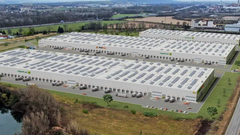 Luftaufnahme eines modernen Logistikparks mit mehreren Lagerhallen, ausgestattet mit Photovoltaikanlagen auf den Dächern.