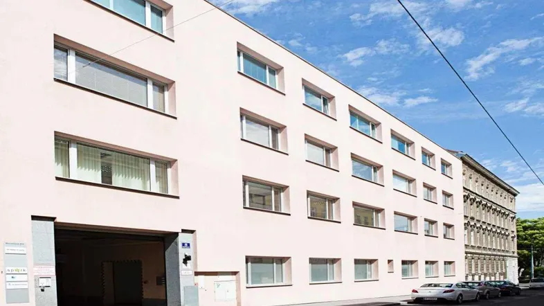 Fassade eines modernen Bürogebäudes mit mehreren Fenstern und einem Garageneingang an einem sonnigen Tag.