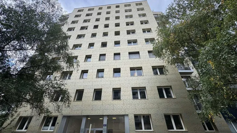 Mehrstöckiges Wohngebäude mit vielen Fenstern und moderner Fassadenverkleidung unter bewölktem Himmel.