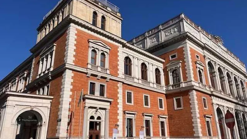 Historisches Gebäude mit roter Ziegelfassade und klassischen Architekturelementen unter blauem Himmel.