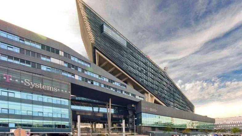 Moderne Bürogebäude mit markanter Architektur und Glasfassaden unter einem bewölkten Himmel.