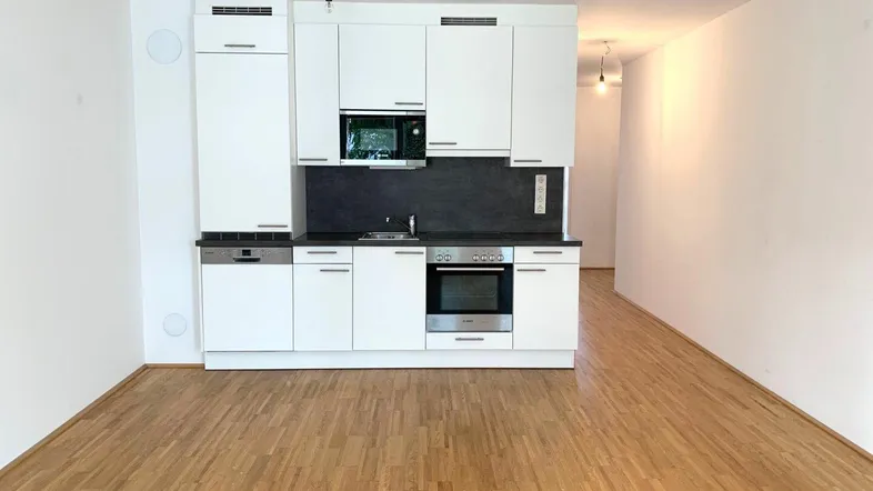 Moderne Einbauküche mit weißen Hochglanzfronten und integrierten Geräten in einem offenen Wohnbereich.