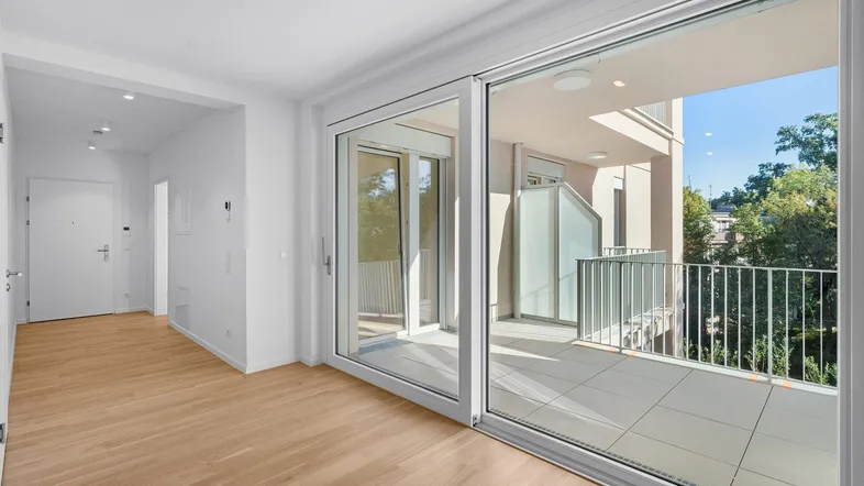 Heller Wohnbereich mit Parkettboden und großzügigem Zugang zum Balkon, ideal für entspanntes Wohnen.