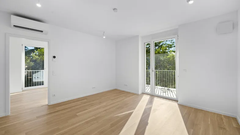 Helles, unmöbliertes Zimmer mit Parkettboden, Klimaanlage und Zugang zu einem französischen Balkon.