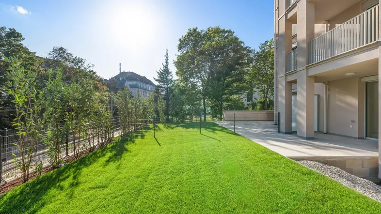 Gepflegter Rasenbereich vor einem modernen Wohngebäude mit sonnigem Ausblick.