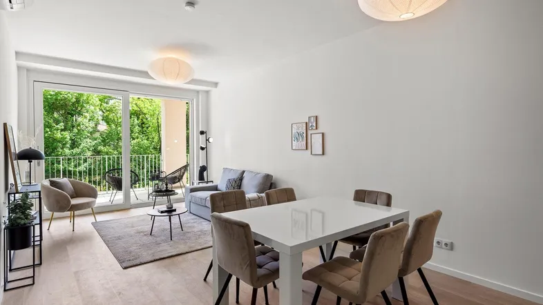 Helles Wohn- und Esszimmer mit Holzboden, modernem Esstisch und Zugang zum Balkon.