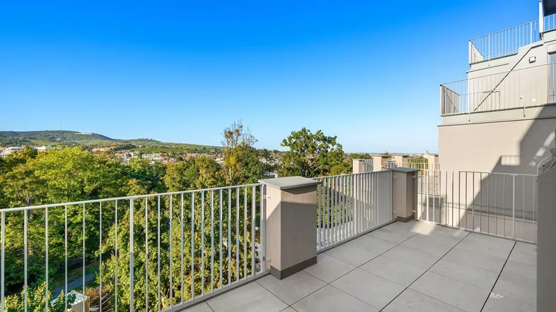 Geräumige Dachterrasse mit weitem Blick über die grüne Umgebung und die Stadt.