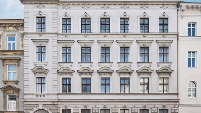 Historisches Gebäude mit klassischer Fassade und modernem Dachausbau in städtischer Umgebung.