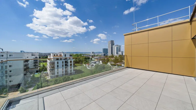 Geräumige Dachterrasse mit Fliesenboden und weitem Blick über die Stadtlandschaft bei blauem Himmel.