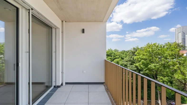 Heller Balkon mit Fliesenboden und Blick ins Grüne, ideal zum Entspannen im Freien.