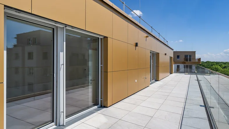 Geräumige Dachterrasse mit Fliesenboden und Glasgeländer, ideal für Entspannung im Freien und Weitblick.