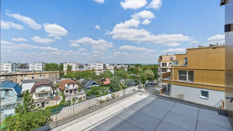 Große Dachterrasse mit Fliesenboden und weitem Blick über die Stadt und umliegende Gebäude.