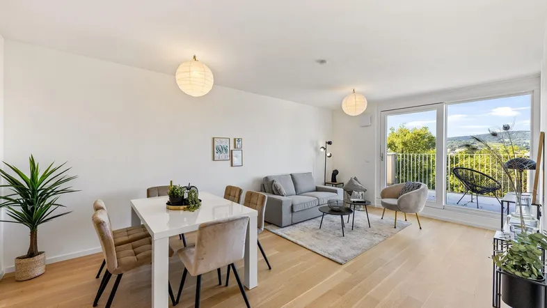 Helles Wohn- und Esszimmer mit Holzboden, Zugang zum Balkon und moderner Einrichtung.