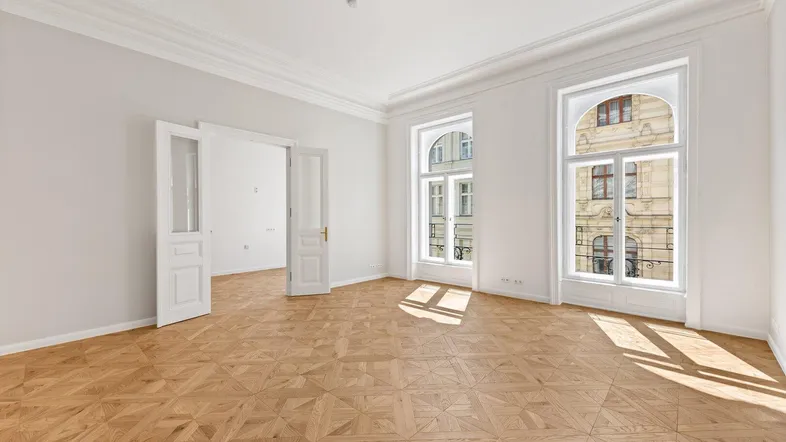 Helles, leeres Zimmer mit Fischgrätparkett und hohen Decken, bereit zur individuellen Gestaltung.