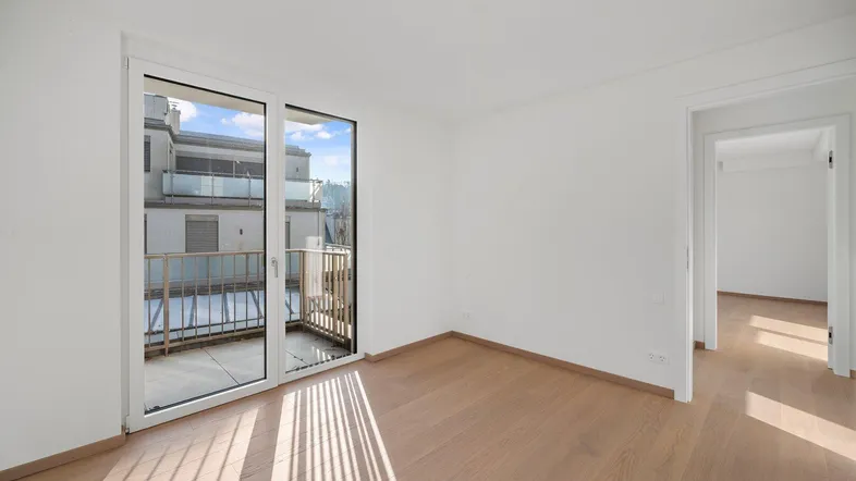 Helles Zimmer mit Holzboden und Zugang zu einem kleinen Balkon, ideal als Schlaf- oder Wohnbereich.