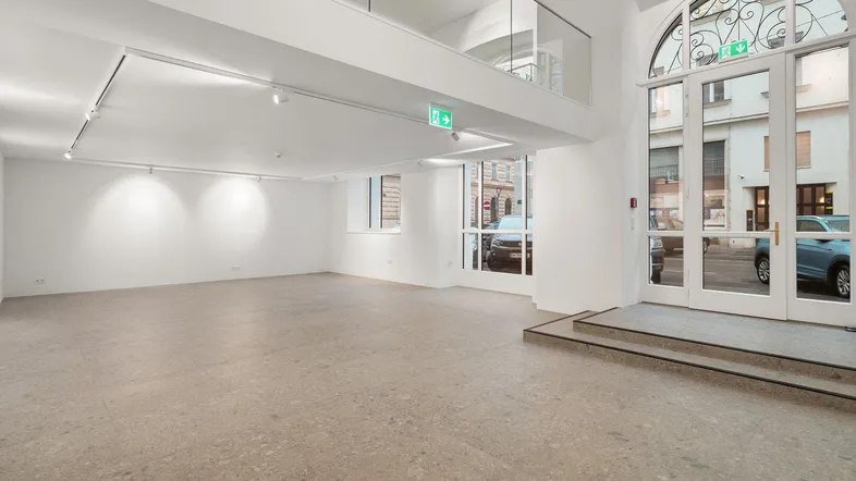 Geräumiger, heller Gewerberaum mit hohen Decken, großen Fenstern und einer Galerieebene.