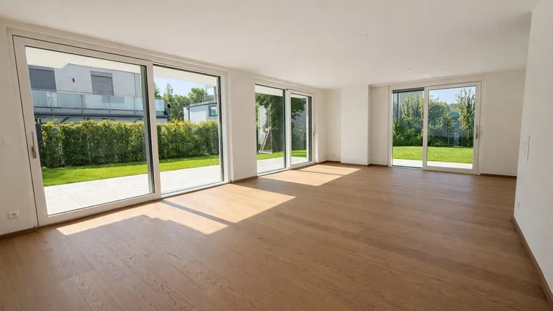 Helles, leeres Wohnzimmer mit großen Schiebetüren und direktem Zugang zum Garten.