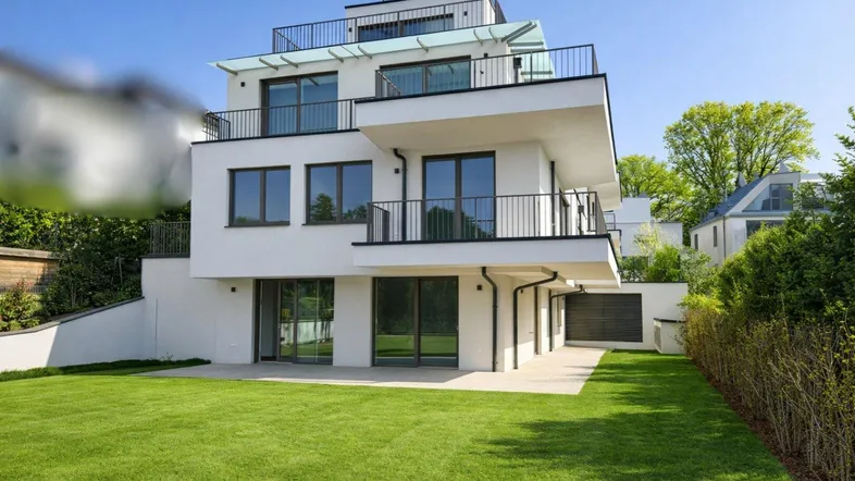 Moderne weiße Villa mit mehreren Balkonen, Dachterrasse und gepflegtem Gartenbereich.
