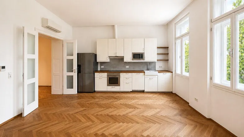 Helle Küche mit weißen Schränken, Holztheke und Fischgrätparkett, offen zum Wohnbereich.