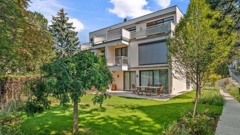 Modernes Mehrfamilienhaus mit gepflegtem Garten, Rasenfläche und Terrasse im Erdgeschoss.