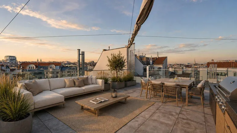 Geräumige Dachterrasse mit Lounge-Möbeln, Essbereich und weitem Blick über die Stadt bei Sonnenuntergang.