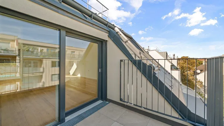 Geräumiger Balkon mit Fliesenboden und Blick auf die Umgebung, zugänglich durch eine große Glasschiebetür.