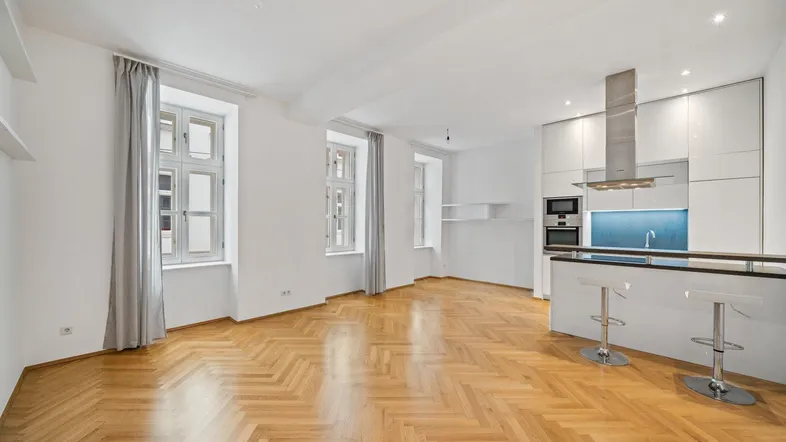 Helles Wohn- und Esszimmer mit moderner offener Küche und Fischgrätparkett.