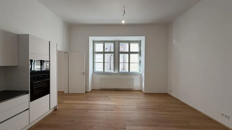 Heller, offener Wohnbereich mit neuer Einbauküche und Parkettboden, ideal für modernes Wohnen.