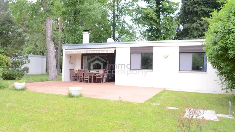 Ansicht des Hauses von außen mit einer möblierten Terrasse und Blick in den grünen Garten.