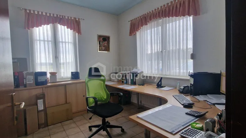 Helles Büro mit zwei Fenstern, Schreibtisch und ergonomischem Stuhl, ideal für konzentriertes Arbeiten.