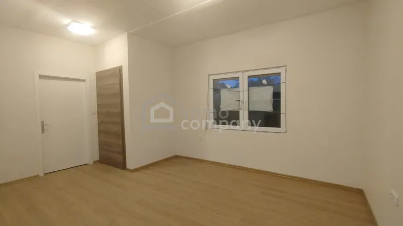 Heller, leerer Raum mit hellem Holzboden, weißen Wänden und einem Fenster, ideal für Schlaf- oder Wohnbereich.